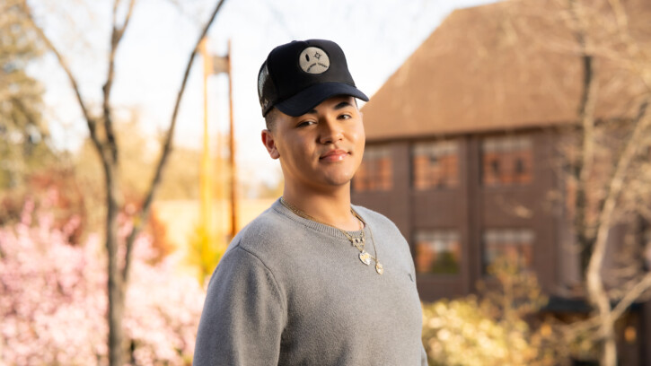 Student looks into the camera while standing outside.