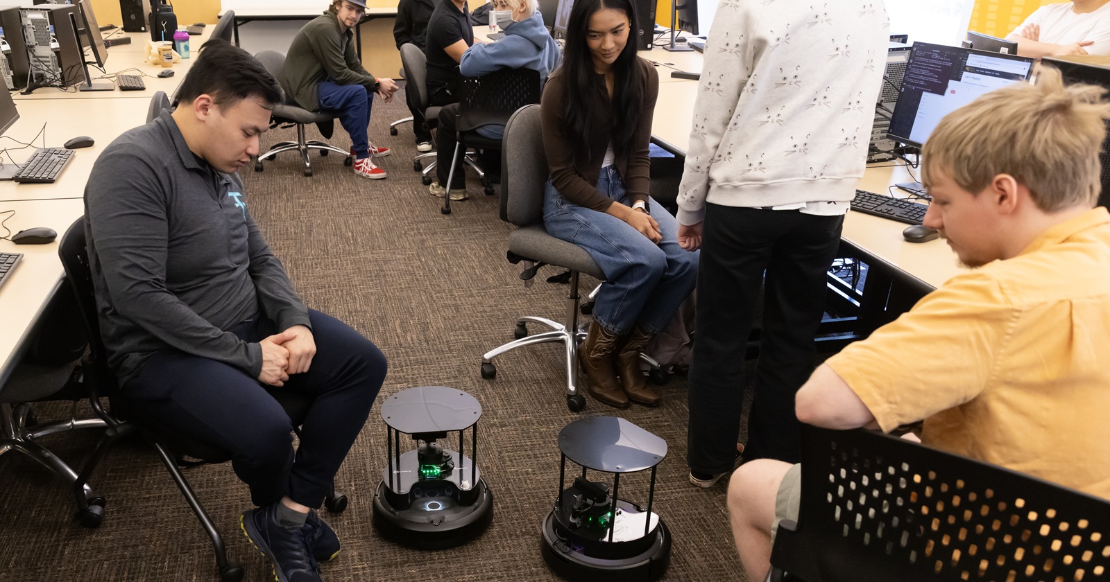 Computer Science students watch the robots they created move on the floor in class.