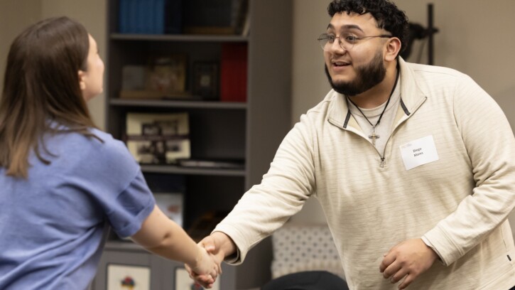 A PLU student and PLU alum shake hands during a Business Networking Dinner on campus.