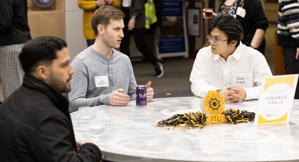 A PLU student listens intently to the alum sitting next to him while at a table during a Business networking dinner held on campus.