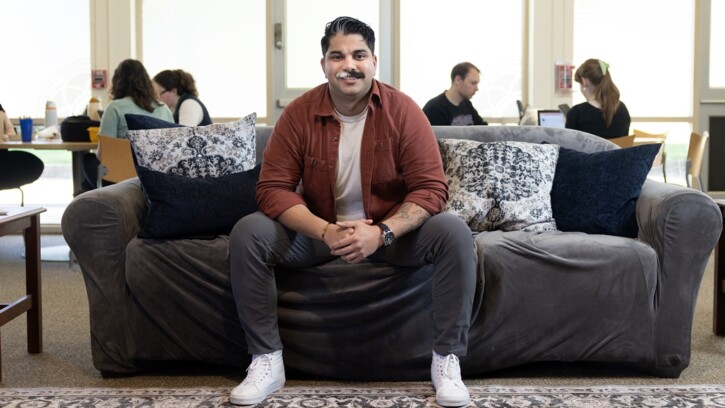 Adrian sits on a couch in the lounge of PLU's Wellbeing Services and Resources space on campus