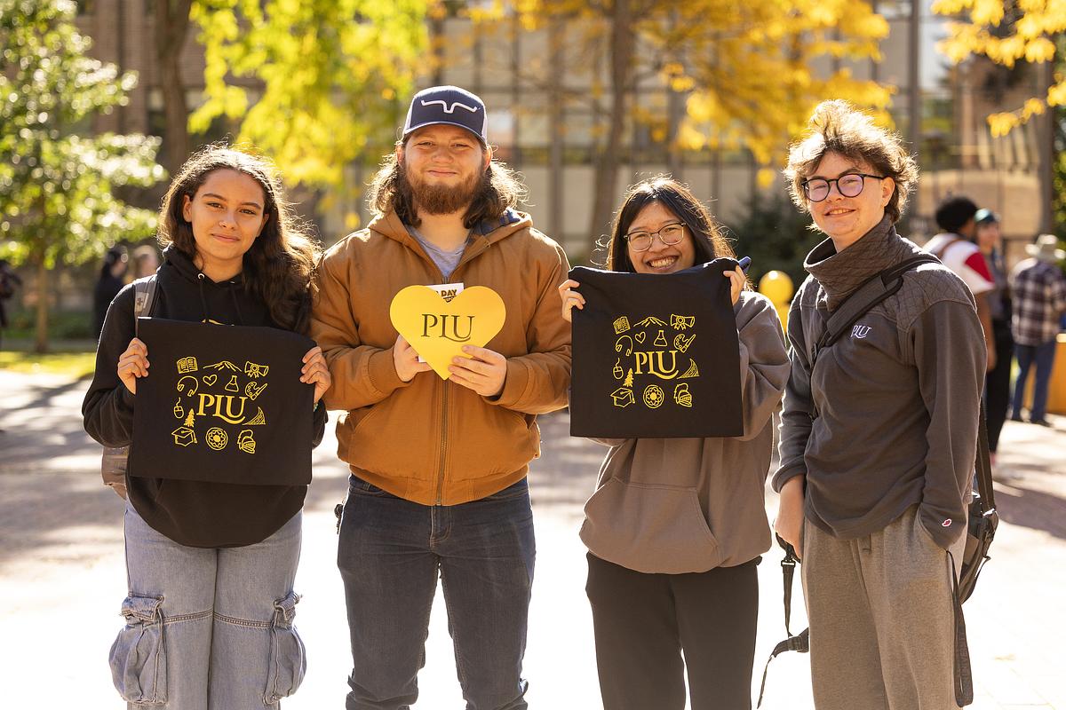 Group of four people posing outdoors wearing university apparel.