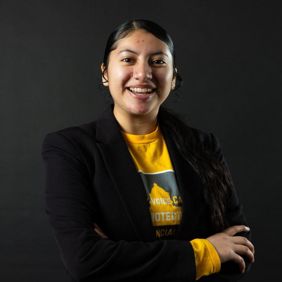 student wearing a black blazer smiles into the camera