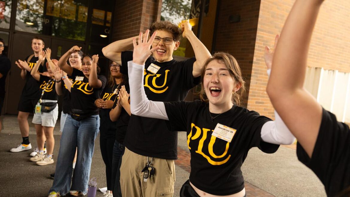 Students stand outside cheering with their hands in the air