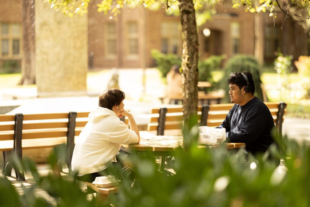 Two students talking outside at a picnic table