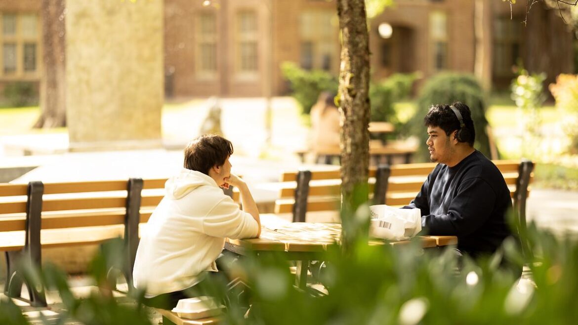 Two students talking outside at a picnic table