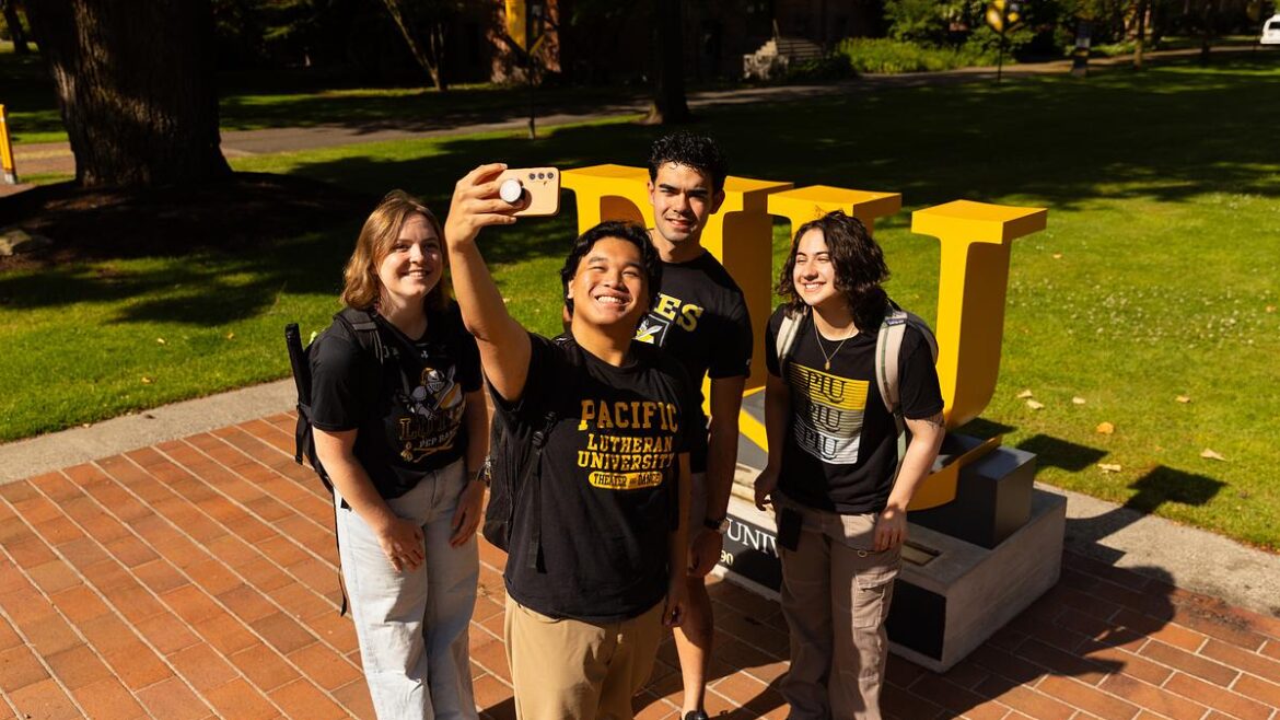 Photo of students wearing PLU gear, outside taking a group selfie.