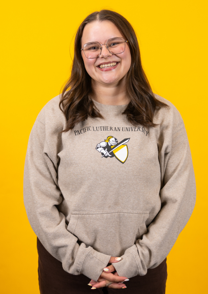 Smiling girl wearing glasses and PLU t-shirt on yellow background