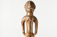 This is a Mossi Figure on a post, which is carved out of wood. The figure has scarification on the face, chest, and thighs, in a style that is found in the Mossi society. The gender is unknown due to the shorts carved on the figure.