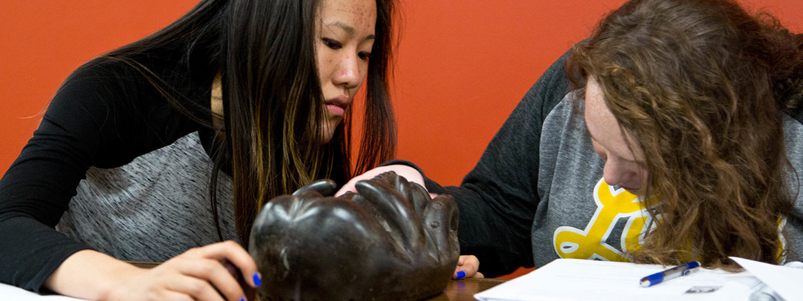 Student Research Team looking at wood carvings