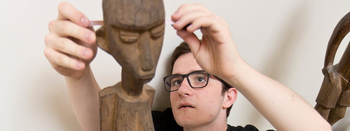 Research Student looking at head of wooden figure