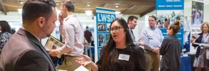 A students talks to a hiring manager at a career fair for education graduates.