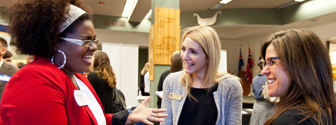 Three women talk at a career fair.