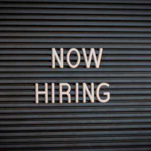 Image of a board with letters "Now Hiring"