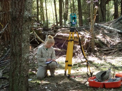 Photo courtesy of the Burke Museum. Emma Holmes using a total station to map the site.
