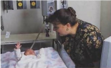 Baby in a hospital crib with a Professor smiling