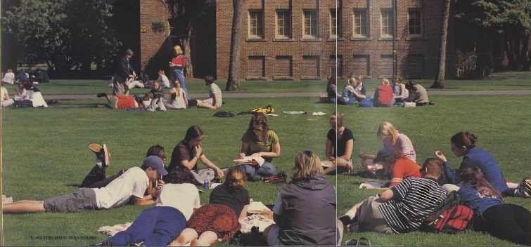 Students sitting outside on the grass having class