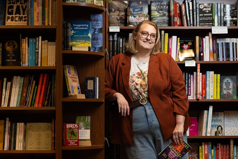 Courtney Gould ’16, author of the genre Queer Horror Fiction, poses for a portrait, Wednesday, July 22, 2026, at Grit City Books in Tacoma. (PLU Photo / Sy Bean)
