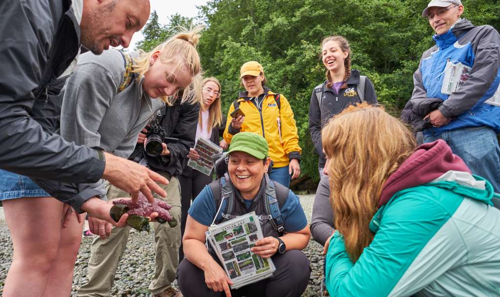 Professor Mike Behrens shows an Ochre Starfish to students (and Professor Heidi Schutz) during a low tide field trip, 2019.