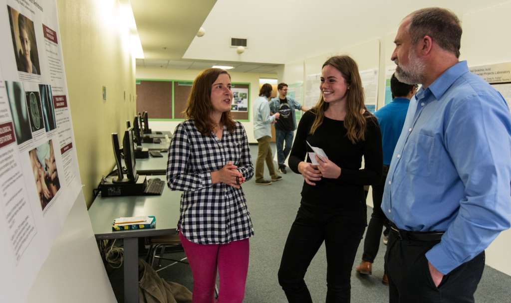 Professor Matt Smith listens to a student's poster presentation in Rieke, 2018