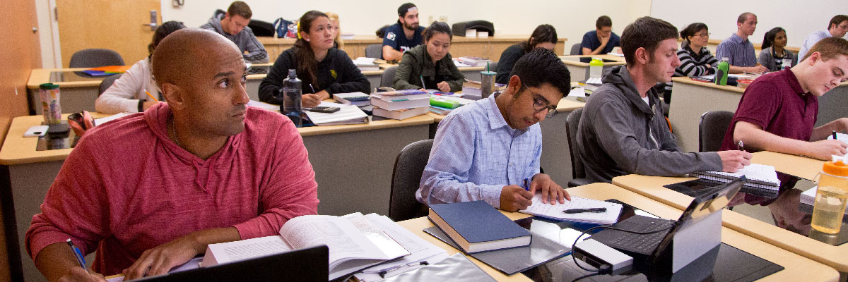 Students in a classroom taking notes while listening to professor