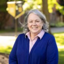 Smiling woman with gray hair wearing blue cardigan outdoors
