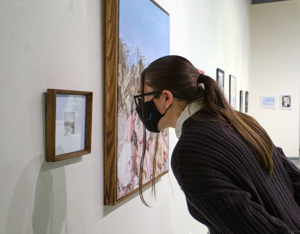 A student examines the original photo of Teagan James's diptych, "Picnic."