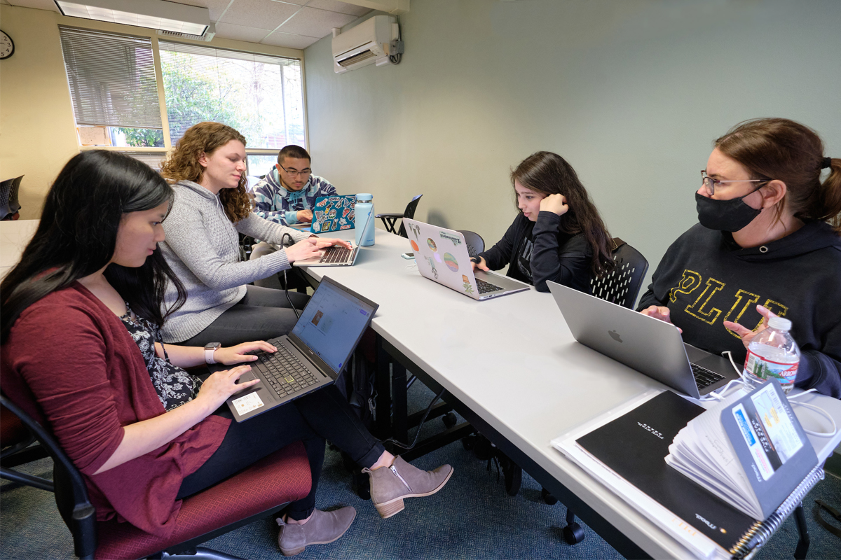 Students work on laptops in a communications class