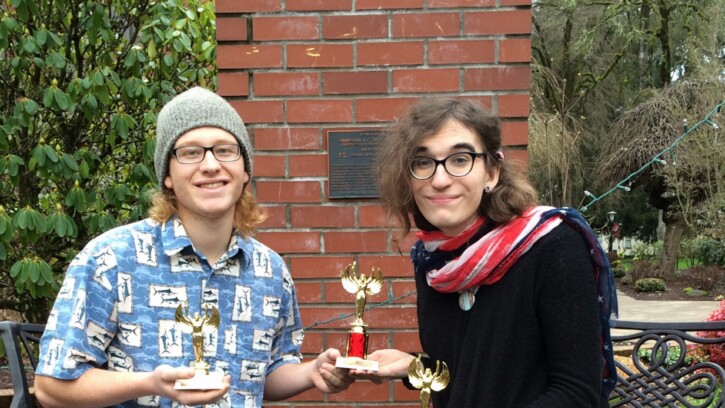 Two Forensics students holding 3 trophys