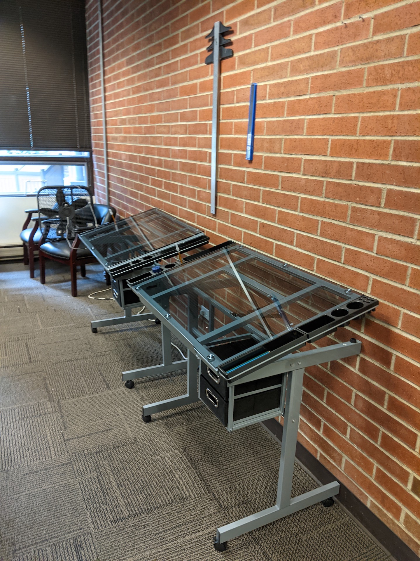 Glass-topped drafting desks along the wall allow students to work on big pieces.