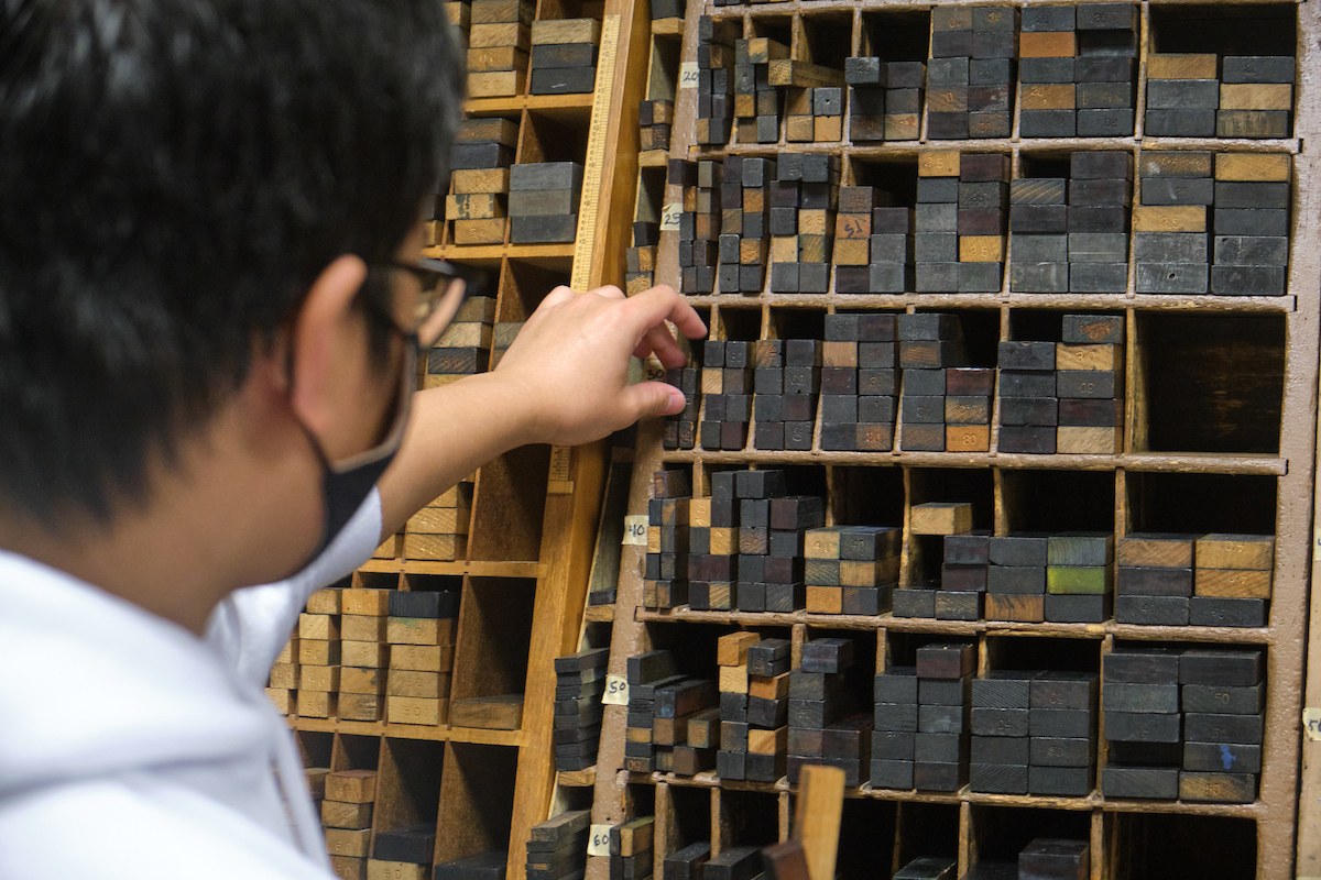 student selecting wooden type from a case on the wall