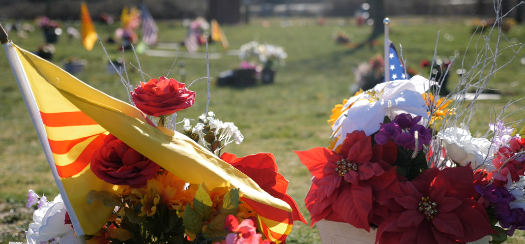 Flowers laid in a cemetery with a South Vietnam flag