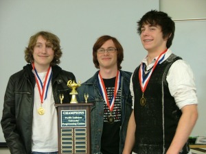 3 students standing by trophy