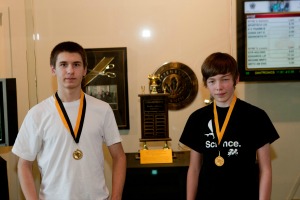 2 students standing by trophy