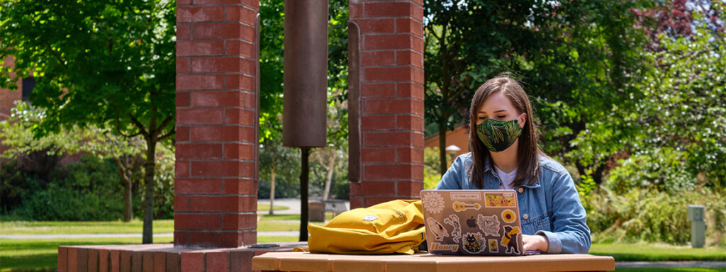 A PLU student in a mask studies in Red Square.