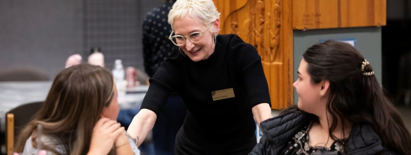 Dr Wendy Gardiner engaging with two students on campus.