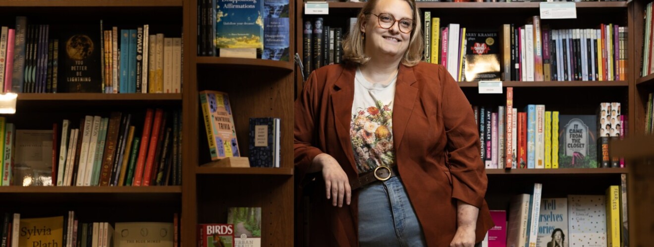 Woman smiling in library surrounded by full bookshelves