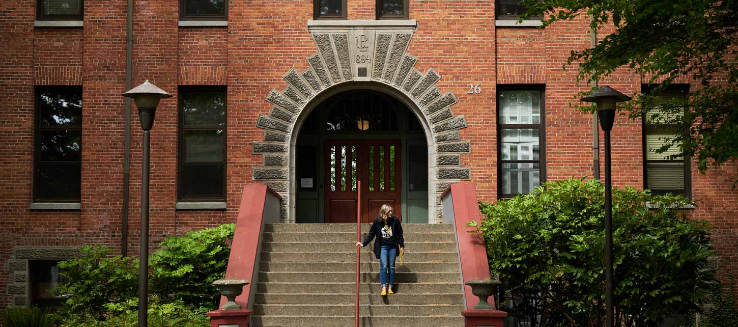 Harstad Hall - an ornate brick building with arched entry and person descending stairs.