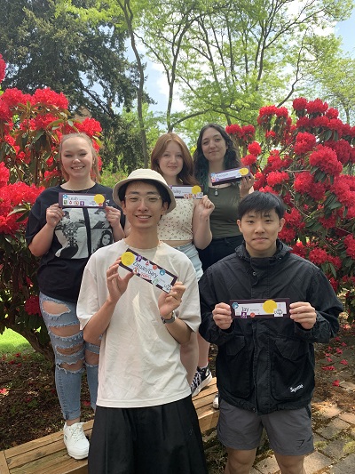 Group 2 from French feminisms class show off their nametags, on which they collected icons all semester long