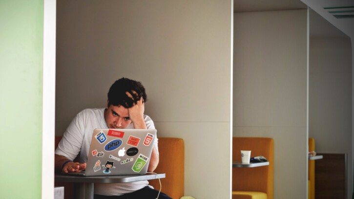 Someone sitting at computer looking frustrated.