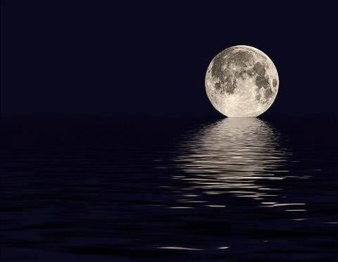 A moon with it's shadow reflected on water.