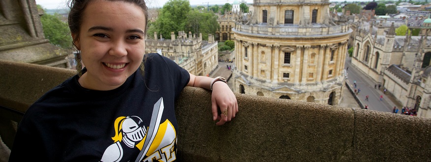 A PLU student in a PLU t-shirt poses for the camera in front of the Radcliffe Camera in Oxford