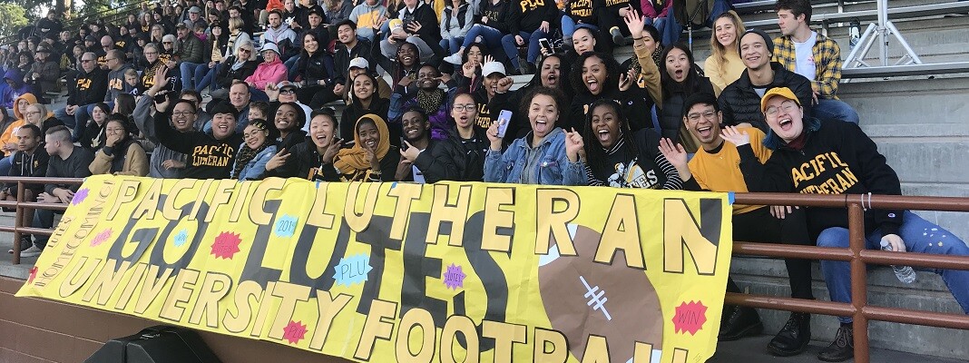 Students with a banner cheer at a PLU football game