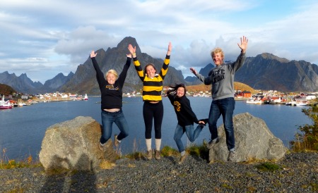 Students happily jumping up in front of a body of water in Lofoten, Norway