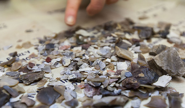 A finger pointing to a pile of rocks and rock shavings