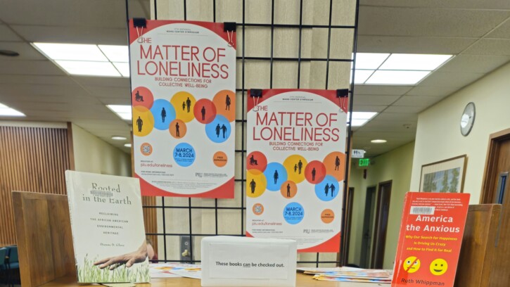 Book display for A Matter of Loneliness Wang Center Symposium. Display is made up of a wooden bookshelf with books standing on the shelves.