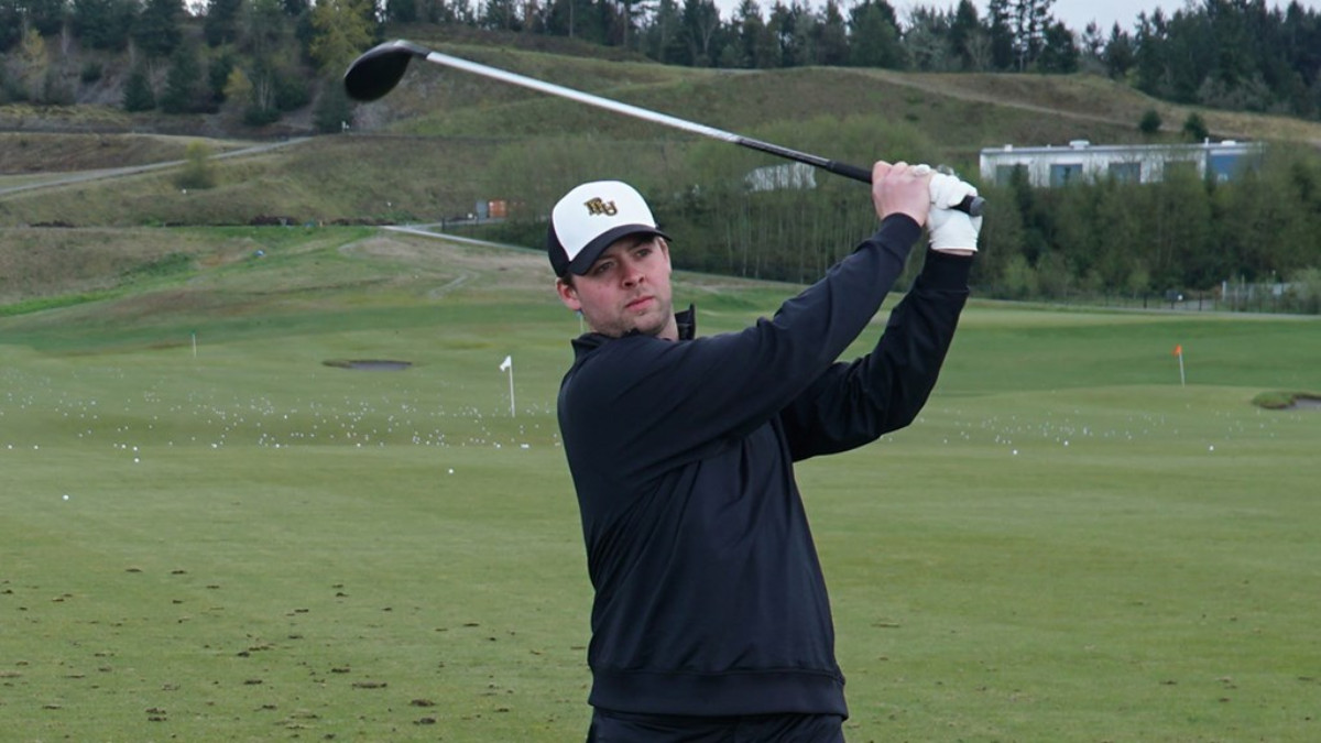 Kyle Drugge is playing at a golf course, holding up his golf club and ready to strike