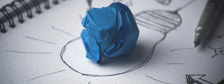 A balled up piece of blue paper in the middle of a drawing of a light bulb to signify a good idea.
