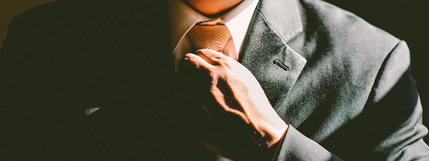 Earn a Post-Baccalaureate Professional Business Certficate Close up of a man straightening his tie.