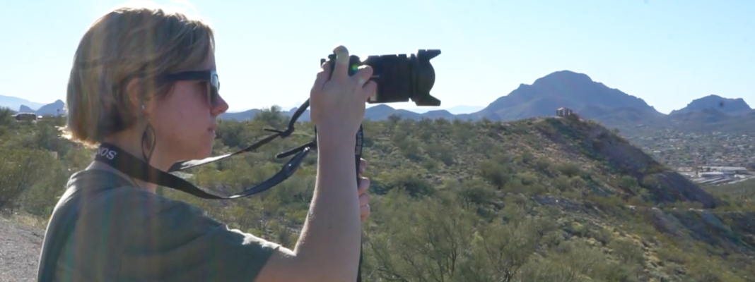 College student using professional camera to record landscape in the Arizona mountains.